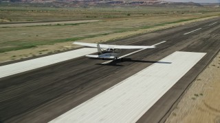 AX139_020E - 5.5K aerial stock footage of tracking Cessna taking off from runway, Canyonlands Field, Utah