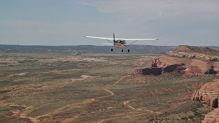 AX139_028E - 5.5K aerial stock footage of a Cessna over desert approaching rock formations, Grand County, Utah