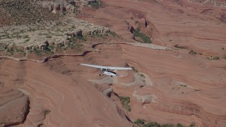 AX139_029 - 5.5K aerial stock footage of a Cessna over desert approaching rock formations, Grand County, Utah