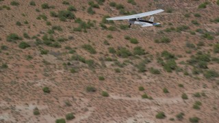 AX139_031 - 5.5K aerial stock footage track a Cessna flying over desert in Grand County, Utah