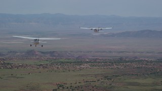 AX139_036 - 5.5K aerial stock footage of tracking Tecnam P2006T over desert, zoom to reveal Cessna, Grand County, Utah