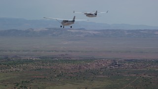AX139_037 - 5.5K aerial stock footage of tracking Tecnam P2006T and Cessna flying over desert, Grand County, Utah