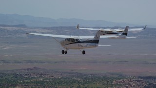 AX139_038 - 5.5K aerial stock footage of tracking Tecnam P2006T and Cessna flying over a desert, Grand County, Utah