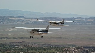 AX139_038E - 5.5K aerial stock footage track a Tecnam P2006T and a Cessna flying over desert, Grand County, Utah