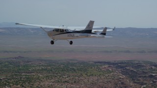 AX139_039 - 5.5K aerial stock footage of Tecnam P2006T and Cessna flying over desert, Grand County, Utah