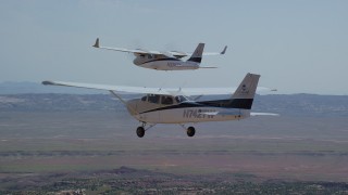 AX139_040 - 5.5K aerial stock footage of a Tecnam P2006T and Cessna flying over wide desert, Grand County, Utah