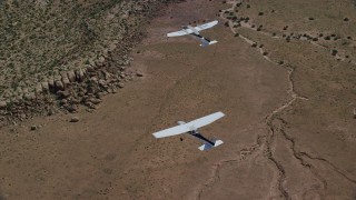 AX139_042 - 5.5K aerial stock footage of tracking Tecnam P2006T and Cessna flying over desert, Grand County, Utah