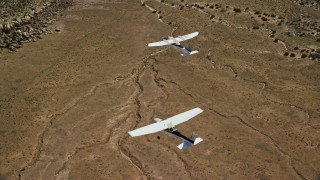 AX139_042E - 5.5K aerial stock footage of Tecnam P2006T and Cessna planes flying over desert, Grand County, Utah