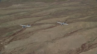 AX139_049 - 5.5K aerial stock footage of Tecnam P2006T and Cessna flying above the desert, Grand County, Utah