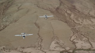 AX139_050 - 5.5K aerial stock footage of Tecnam P2006T, Cessna flying over desert, zoom out, Grand County, Utah