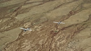 AX139_050E - 5.5K aerial stock footage of Tecnam P2006T, Cessna flying over desert, zoom out, Grand County, Utah