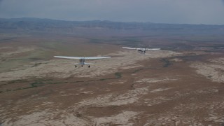 AX139_053 - 5.5K aerial stock footage of tracking Tecnam P2006T and Cessna planes flying over desert, Grand County, Utah