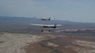 AX139_056 - 5.5K aerial stock footage of following Tecnam P2006T and Cessna flying over desert, Grand County, Utah