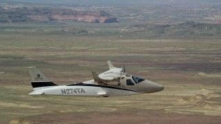 AX139_065E - 5.5K aerial stock footage of tracking Tecnam P2006T and Cessna aircraft flying over desert, Grand County, Utah