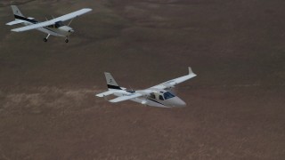 AX139_068 - 5.5K aerial stock footage of tracking Tecnam P2006T and Cessna aircraft flying over desert, Grand County, Utah