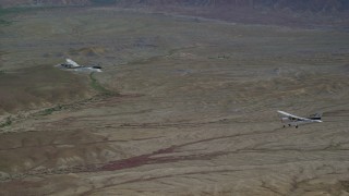 AX139_073 - 5.5K aerial stock footage of tracking Tecnam P2006T and Cessna aircraft flying over desert, Grand County, Utah