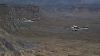 AX139_075 - 5.5K aerial stock footage focus on Tecnam P2006T and Cessna flying over desert, Grand County, Utah