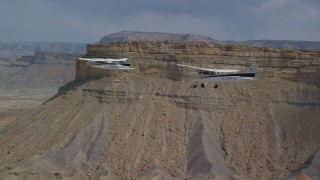 AX139_077 - 5.5K aerial stock footage of tracking Tecnam P2006T and Cessna flying by desert mesas, Grand County, Utah