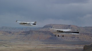 AX139_078 - 5.5K aerial stock footage focusing on Tecnam P2006T and Cessna flying over desert, Grand County, Utah