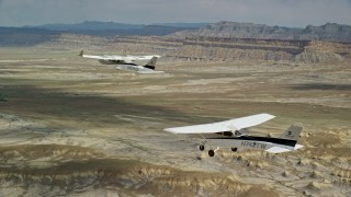 AX139_084E - 5.5K aerial stock footage of air to air view of Tecnam P2006T and Cessna flying over desert, Grand County, Utah