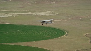 AX139_092E - 5.5K aerial stock footage video of a Cessna airplane over circular crop field, Green River, Utah