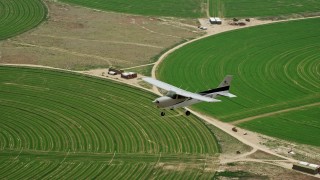 AX139_096E - 5.5K aerial stock footage of an air to air view of a Cessna over circular crop fields, Green River, Utah