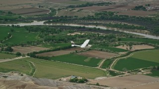 AX139_098 - 5.5K aerial stock footage of tracking Cessna over farmland and desert hills, Green River, Utah