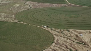 AX139_099 - 5.5K aerial stock footage of a lone Cessna over circular crop fields, Green River, Utah