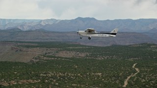 AX139_112E - 5.5K aerial stock footage pan to reveal and track Cessna flying over desert mesas, Emery County, Utah
