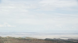 AX139_119E - 5.5K aerial stock footage of tracking Cessna over desert near ridge, ascend out of frame, Emery County, Utah