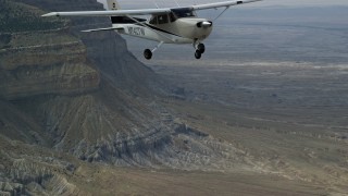 AX139_123E - 5.5K aerial stock footage of a Cessna flying high above desert, near mountains, Emery County, Utah