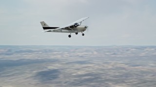 AX139_125 - 5.5K aerial stock footage of tracking a Cessna flying high above desert, partly cloudy, Emery County, Utah