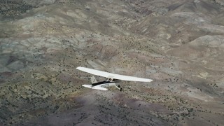 AX139_131E - 5.5K aerial stock footage focus on a Cessna in flight high above desert vegetation, Emery County, Utah