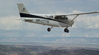 AX139_139 - 5.5K aerial stock footage zoom out from tail and track Cessna over desert, Emery County, Utah