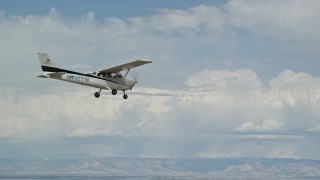 AX139_140E - 5.5K aerial stock footage fly beside a Cessna in flight over desert mountains, partly cloudy, Carbon County, Utah
