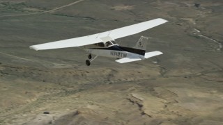 AX139_148E - 5.5K aerial stock footage track a Cessna aircraft flying over desert, mountains in distance, Carbon County, Utah