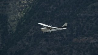 AX140_021E - 5.5K aerial stock footage of Cessna over desert mountains and mountain road, Carbon County, Utah
