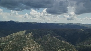 AX140_025E - 5.5K aerial stock footage zooming in on a Cessna over desert mountains, partly cloudy day, Carbon County, Utah