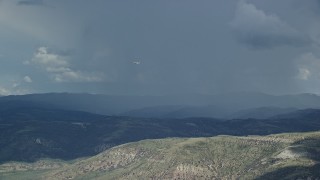 AX140_039E - 5.5K aerial stock footage of a Tecnam P2006T airplane flying by rainstorm, Wasatch Range, Utah