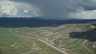 AX140_041E - 5.5K aerial stock footage track a distant Tecnam P2006T by a rainstorm and Highway 6, Wasatch Range, Utah County, Utah