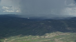 AX140_043E - 5.5K aerial stock footage of focusing on a Tecnam P2006T airplane as it passes a rainstorm, Wasatch Range, Utah