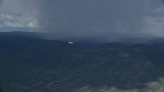 AX140_044 - 5.5K aerial stock footage of focusing on a Tecnam P2006T airplane as it passes a rainstorm, Wasatch Range, Utah