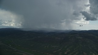 AX140_046 - 5.5K aerial stock footage wide view of a Tecnam P2006T and Cessna flaying by rainstorm, Wasatch Range, Utah
