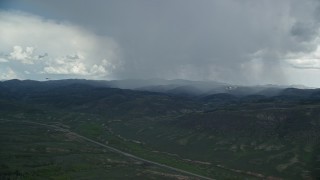 AX140_047E - 5.5K aerial stock footage track distant Tecnam P2006T and Cessna near rainstorm and Highway 6, Wasatch Range, Utah
