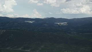 AX140_050E - 5.5K aerial stock footage of tracking Tecnam P2006T from behind Cessna flying by mountains, Wasatch Range, Utah