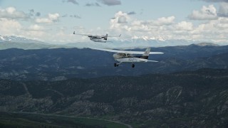AX140_054E - 5.5K aerial stock footage track Cessna flying with Tecnam P2006T near mountains and Highway 6, Wasatch Range, Utah