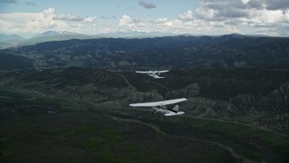 AX140_058E - 5.5K aerial stock footage of tracking a Cessna flying with a Tecnam P2006T by mountains, Wasatch Range, Utah