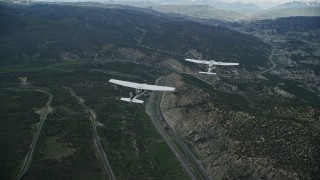 AX140_063E - 5.5K aerial stock footage of a Tecnam P2006T leading a Cessna over mountains and Highway 6, Wasatch Range, Utah
