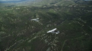 AX140_080E - 5.5K aerial stock footage of flying around a Tecnam P2006T leading a Cessna over mountains, Wasatch Range, Utah