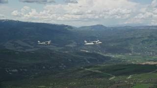 AX140_084E - 5.5K aerial stock footage of tracking Tecnam P2006T, Cessna flying near snowy mountains in the Wasatch Range, Utah